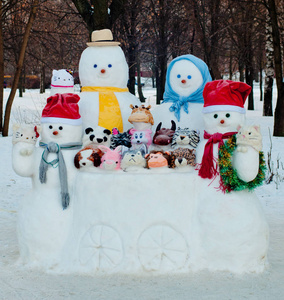 冬天，一群穿着不同尺寸的雪人和雪地动物在户外靠近树木
