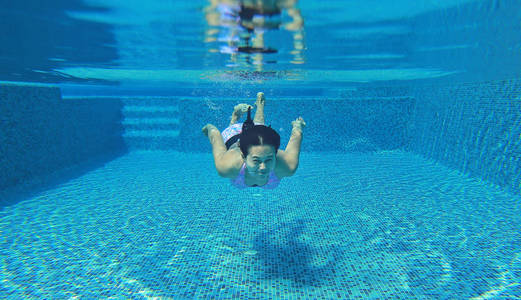 水下拍摄的年轻女人在游泳池里跳水