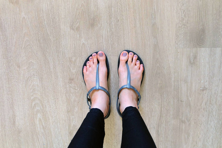 夹足夹女孩腿和脚穿黑色凉鞋在木背景照片