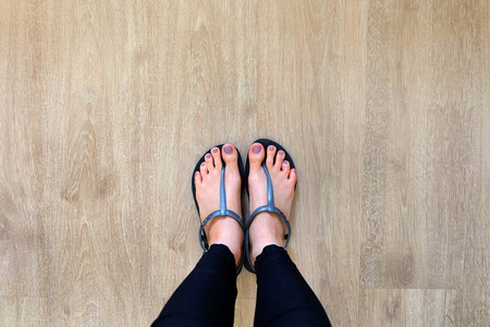 女孩腿和脚穿黑色凉鞋在木背景照片