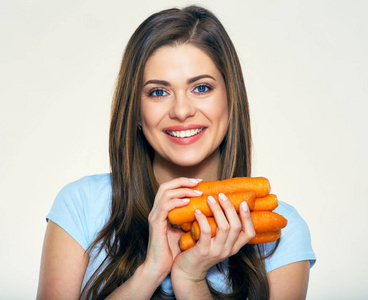 微笑的年轻女子拿着一堆胡萝卜，健康的食物概念