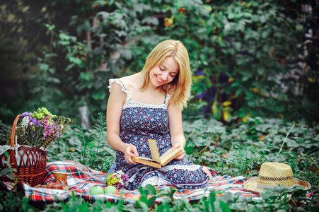 美丽的年轻女子在乡下野餐。户外快乐的一天。打开。微笑的女人, 手里拿着书, 在公园里放松。娱乐
