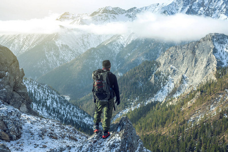 徒步旅行者背着背包在山顶上, 看着雪坡。概念动机与目标成就