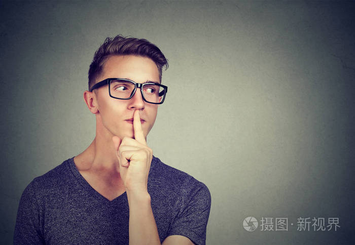 秘密的家伙.男人说嘘安静的手指放在嘴唇手势到一边看