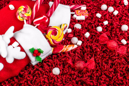 圣诞袜充满糖果和糖果的红色蓬松背景。平躺。复制空间