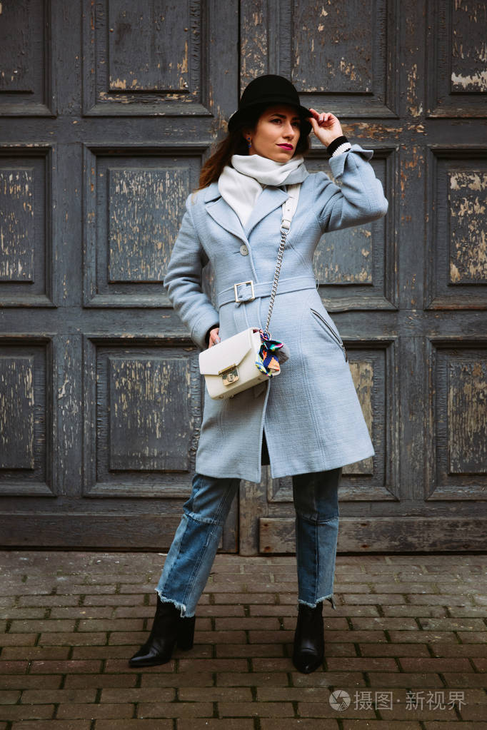 户外的年轻漂亮的时尚女孩在街上摆姿势的全身肖像.模型看一边.