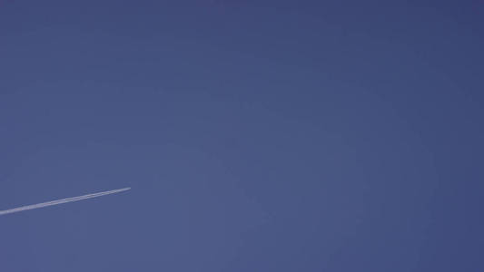 大乘客超音速飞机高高地飞在清澈的蓝天下, 留下了漫长的白色足迹。飞机在蓝天白云中飞翔。飞行蓝天的飞机