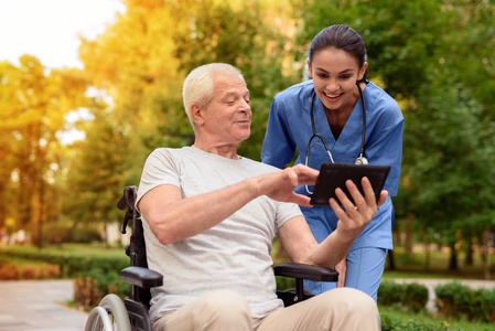 一个坐在轮椅上的老人自豪地在他的石碑上展示了一个快乐的护士