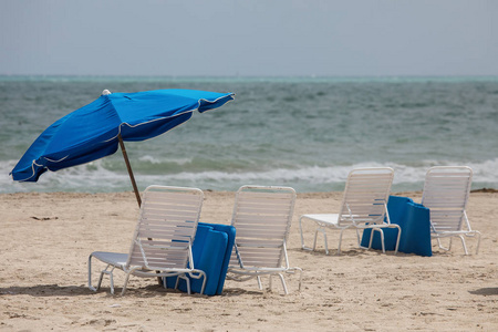 迈阿密南部海滩的蓝色雨伞和白躺椅