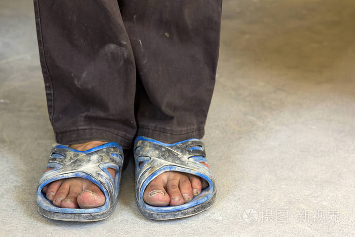 穿着旧脏衣服和鞋子的人的脚