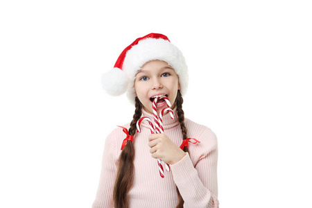 年轻女孩在圣诞老人帽子与圣诞糖果在白色 backg