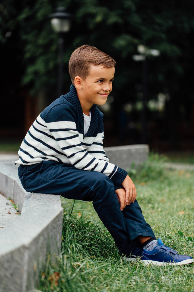 年轻的小男孩坐在路边