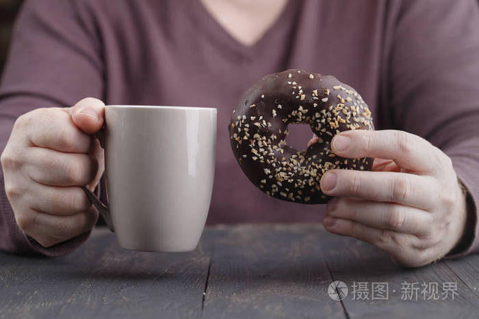 男子手持釉面圈和咖啡杯