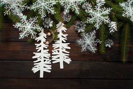 绿色生活云杉树枝在一个黑暗的木背景。新的一年背景与锥体和白色的雪花和纸板圣诞树。顶部视图