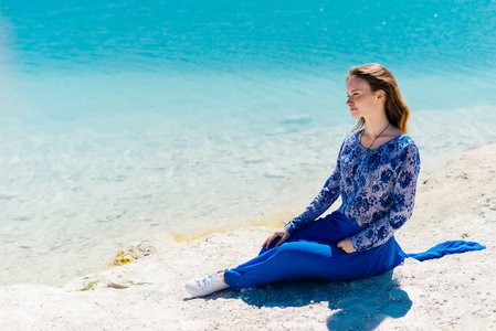 的年轻女性旅行者坐在海滩上放松，期待 copyspace 蓝色的水背景。享受夏天太阳的光芒，自由快乐的概念
