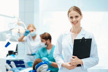 一个护士对一个女孩的牙齿的牙医的背景摆姿势