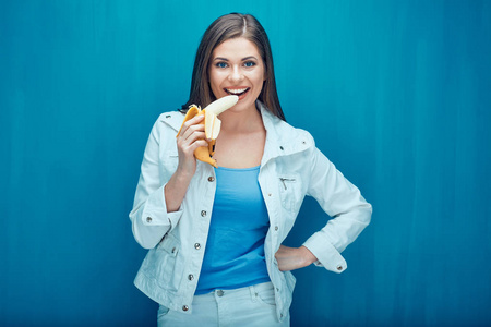 微笑的女士在蓝色背景上吃香蕉