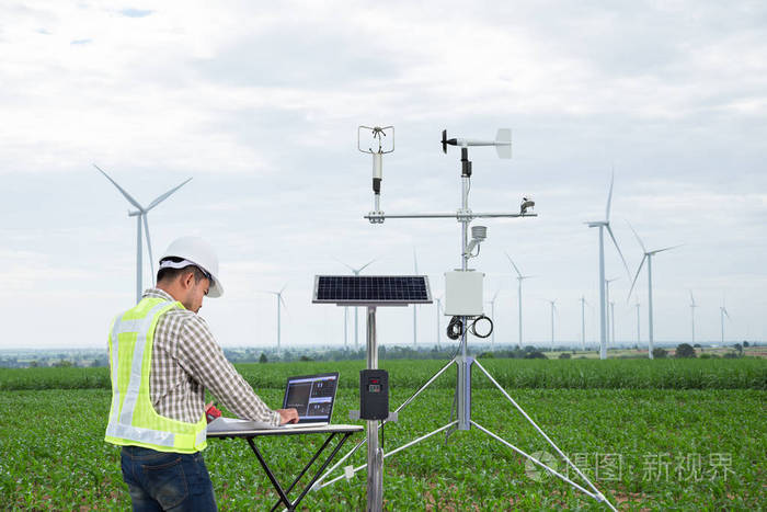 工程师使用平板电脑收集数据用气象仪器测量风速温湿度和太阳电池系统