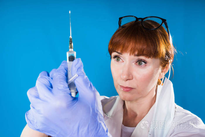 成人red-haired 女医生戴着蓝色手套手里拿着注射器