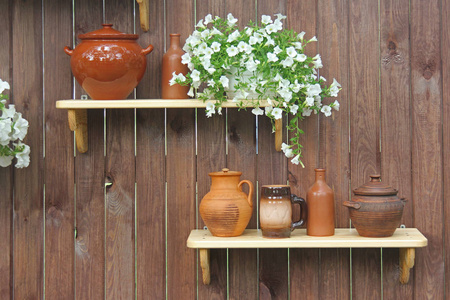 陶器壶和壶站在一个架子上的背景下的木墙