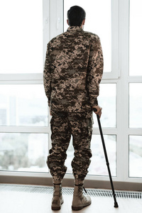 一个残废的士兵靠在靠窗的拐杖上。他看着大全景窗口