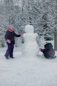 快乐的孩子们在白雪覆盖的公园里享受冬天的气氛，玩耍和堆雪人