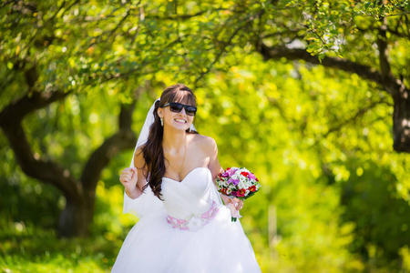 美丽的新娘在太阳镜在公园里摆姿势