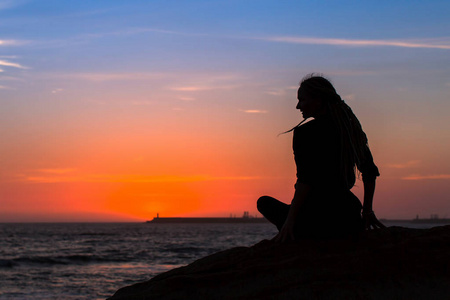 在黄昏时分，坐在海边长着可怕的长柄瑜伽女人。