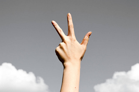 三个手指敬礼手势,在天空背景上照片