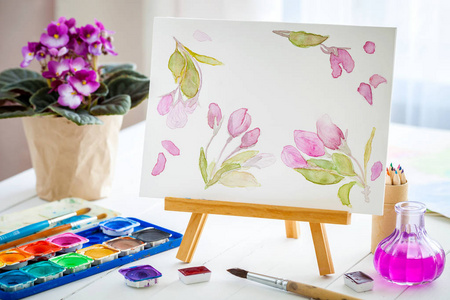 画布上的画架, 水彩素描, 油漆, 刷子和紫色 senpolia 花壶