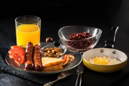 全英早餐与炒鸡蛋在煎锅, 培根, 香肠, 豆类, 西红柿和果汁