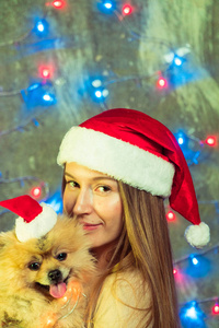 一个女孩在圣诞节帽子与狗博美博美
