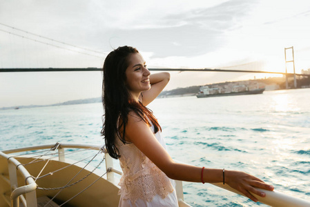 一个年轻的女孩旅行者放松在游艇巡航, 理顺她的头发, 享受日落
