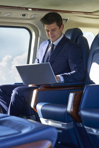 商人在飞行期间直升机座舱笔记本电脑上工作