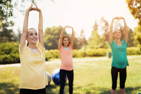 怀孕瑜伽三名怀孕妇女站在公园里做运动