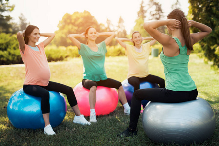 怀孕瑜伽三怀孕妇女在公园瑜伽。他们和教练一起做练习