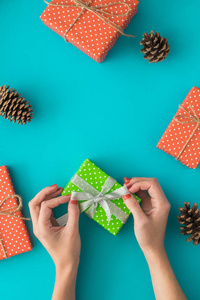 圣诞节和新年假期的组合与礼品盒, 松树锥, 妇女的手包在蓝色的背景礼物。顶部视图, 平躺。Copyspace