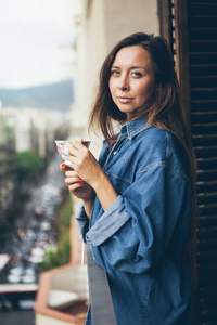 美丽的女人在她的公寓阳台上喝杯茶, 街景