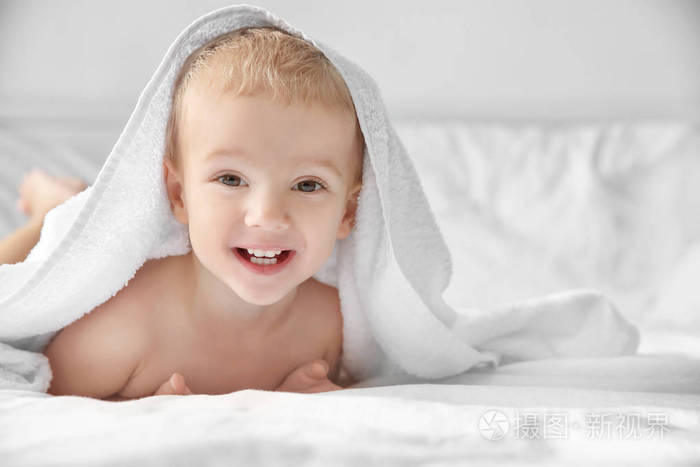 可爱的小男孩在床上的毛巾在家里