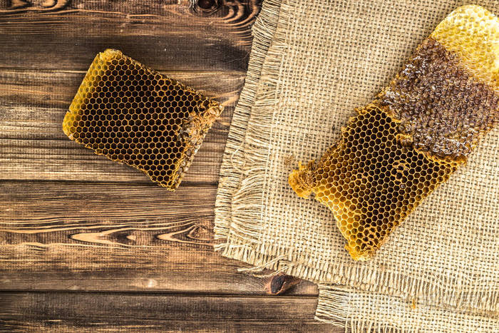 蜂窝与蜂蜜在质朴的木材背景覆盖黄麻麻布顶部视图