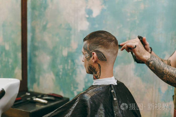 近距离拍摄的人在理发店流行发型男性发型师在纹身服务客户