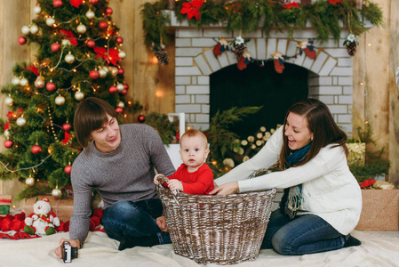 年轻顽皮的快乐的父母与一个可爱的小男孩在家里装饰房间的肖像。圣诞节好心情。新年。生活方式家庭和团结概念