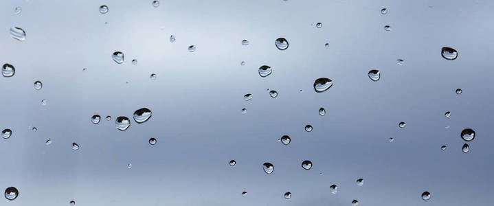 雨点落在透明的玻璃背景上照片