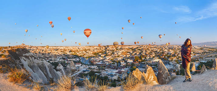 山顶上的一个旅游女孩, 享受着日出和气球的美景。愉快的旅行在土耳其概念
