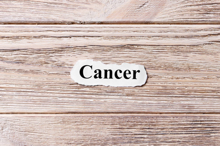 癌症的字在纸上。概念.木制背景下的癌症词汇