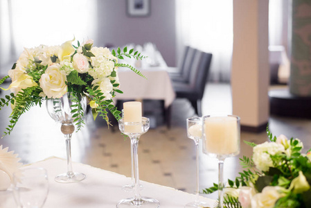 内部的婚礼装饰。桌上白花。用水晶眼镜为桌子服务