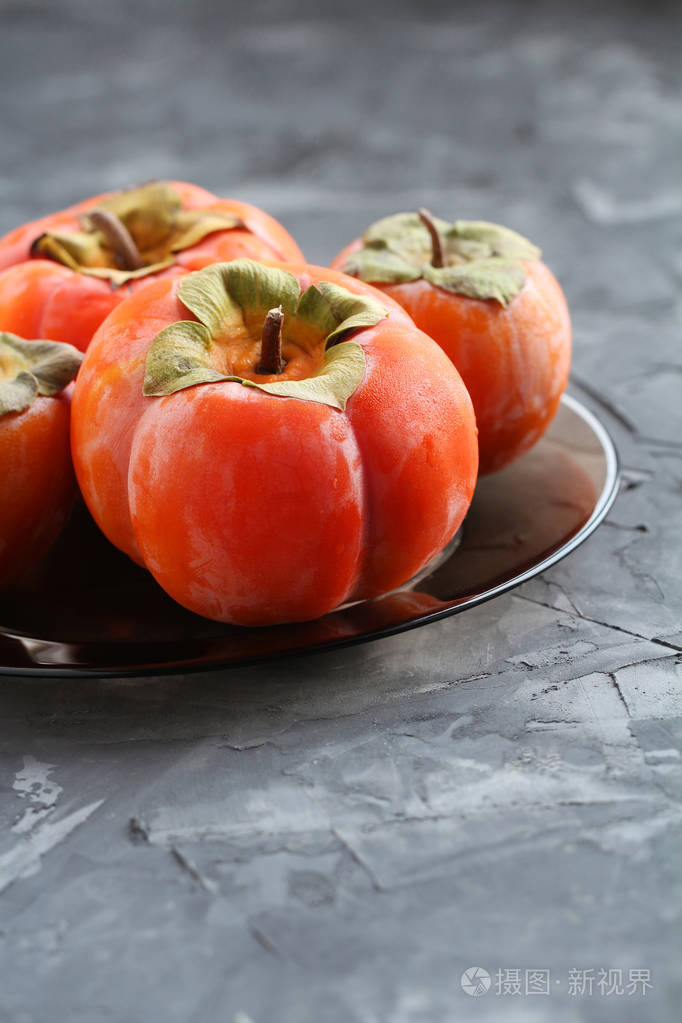 在一个具体背景的盘子上的柿子