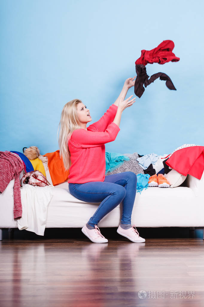 坐在凌乱的沙发上扔衣服的女人