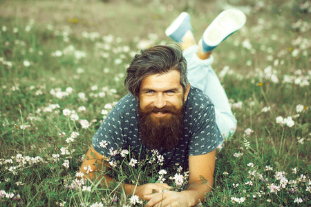 有胡子的人躺在绿色的草地上微笑