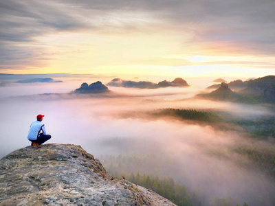 孤独在裸露的岩石首脑会议上的时刻。黑衣男人欣赏奇妙的景色。徒步旅行者坐在山顶上